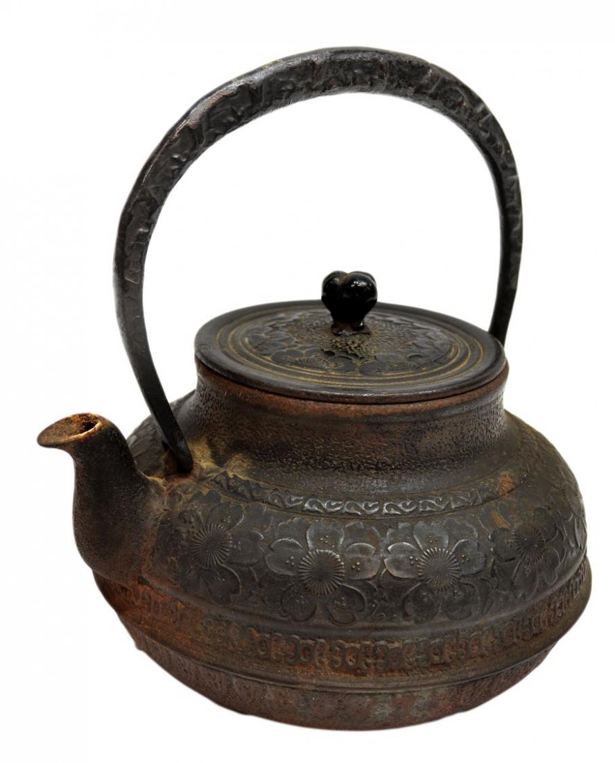 JAPANESE CAST IRON OVOID KETTLE: Japanese cast iron kettle, of compressed ovoid form with a tall loop handle and a curved spout, decorated with a low relief band of cherry blossoms framed by narrow geometric bands on the shoulder, th