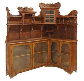 ART NOUVEAU CARVED OAK CORNER DISPLAY CABINET: Art Nouveau period carved oak corner display cabinet/ vitrine, early 20th c., having shaped crest with carved floral motifs, over central corner cabinet with inset beveled glass panes, flanked by open