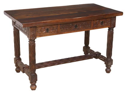 SPANISH BAROQUE STYLE WALNUT LIBRARY TABLE: Spanish Baroque style walnut library desk, 20th c., having three-plank tabletop with separation between panels, over three foliate carved drawers, rising on waved legs, joined with center stretcher, r