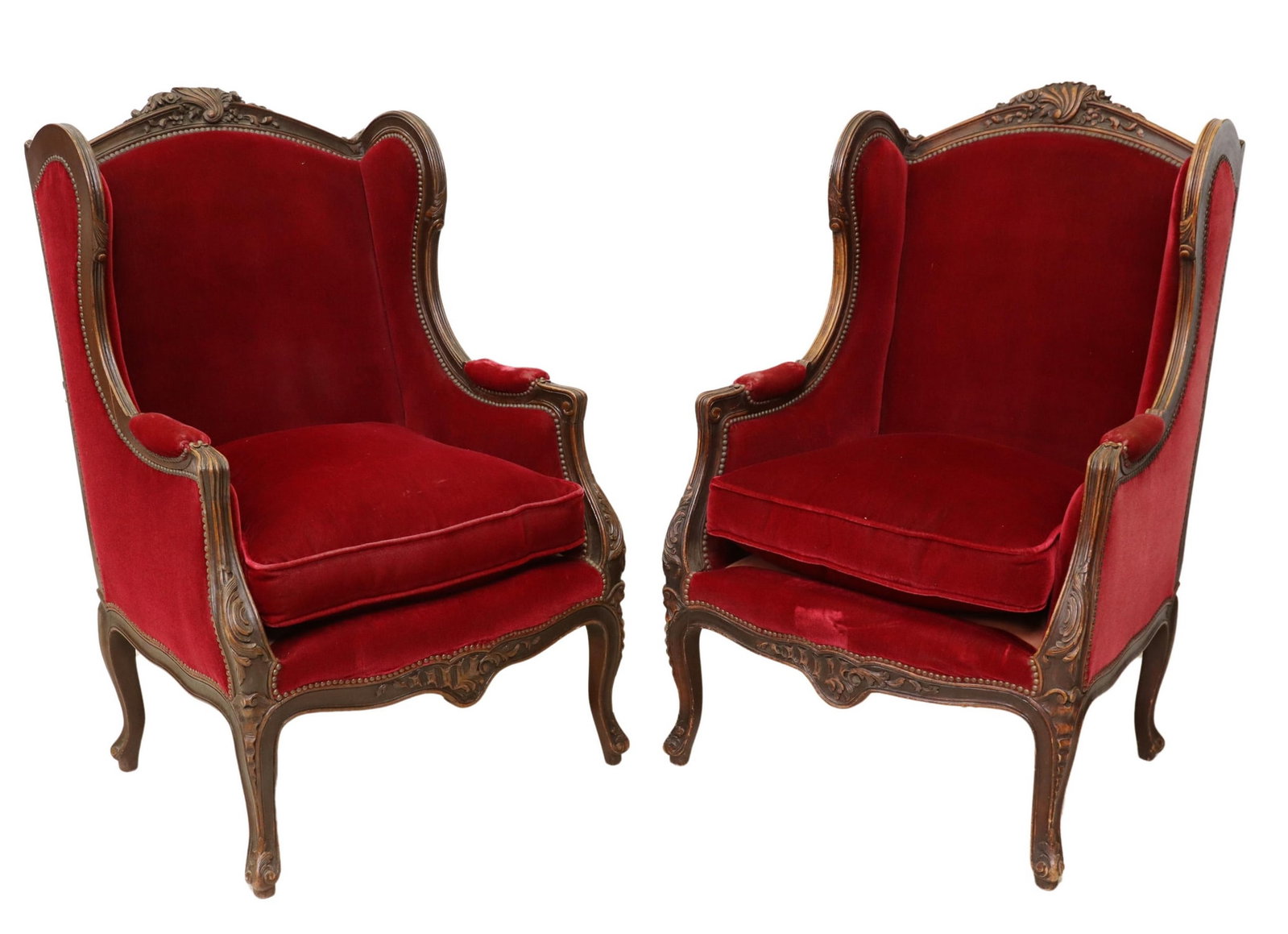 (2) FRENCH LOUIS XV STYLE WINGBACK BERGERES: (pair) French Louis XV style wingback armchairs, 20th c., having scrolled carvings throughout, worn red velvet upholstery with nailhead trim, removable cushion seat, rising on cabriole legs, some wear