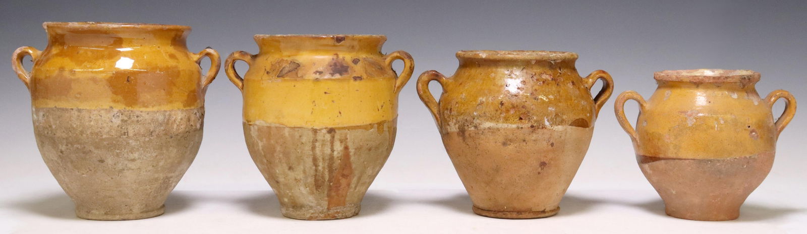 (4) FRENCH YELLOW-GLAZED EARTHENWARE CONFIT POTS: (lot of 4) French Provincial earthenware confit jars, with ochre-glazed rims, pulled handles, all with typical glaze losses, small chips, largest: approx 8"h; 10lbs total Start Price: $200.00