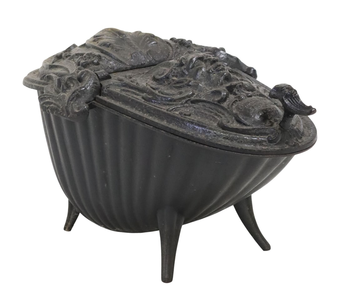 FRENCH CORNEAU FRERES CAST IRON COAL HOD, 19TH C.: French cast iron coal hod, Corneau Freres, Charleville, Ardennes, 19th c., hinged lid with classical mask framed by foliage and c-scrolls, on tapering splayed legs, approx 13.5"h, 23.5"l, 15.5"w Start