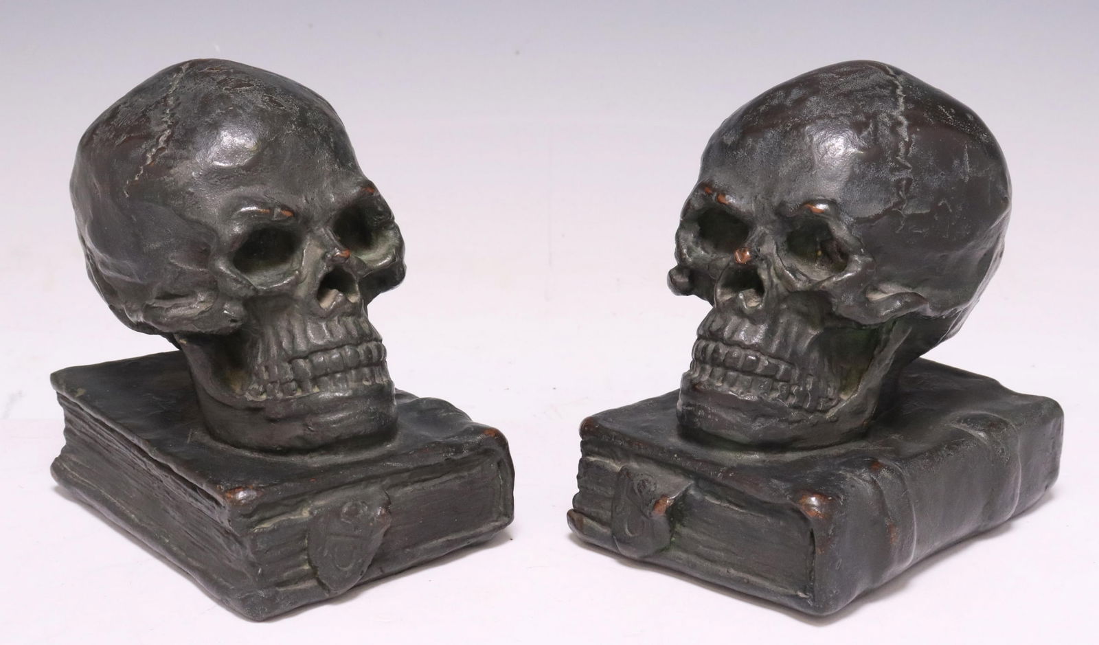 (2) AMERICAN BRONZE-CLAD SKULL & BOOK BOOKENDS: (pair) American "armor bronze" (bronze cast over an everlasting core) bookends, National Metalizing Company, New York, early 20th c., each modeled as a human skull on a book, approx 5.25"h, 5"w, 3.75"