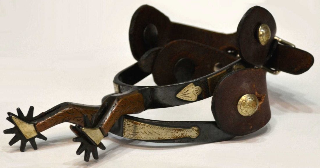 (PAIR) GAL LEG WESTERN COWBOY SPURS: (pair) Gal leg western spurs, silver color arrowheads on outside heel band, 10 point 1.3/16" rowels, leather straps, floral design on buttons, no makers mark, shank inside: 3.1/8"w, 3.25"d, 1lb Start 