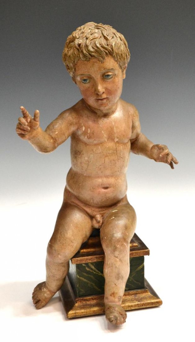 ANTIQUE RELIGIOUS CARVED WOOD CHRIST CHILD, SPAIN: A figure of the Christ Child, Madrid, Spain, 19th c., gesso over the carved wood figure with serene face and pale blue eyes, seated upon a parcel gilt marbelized wood base, restorations / some loss to