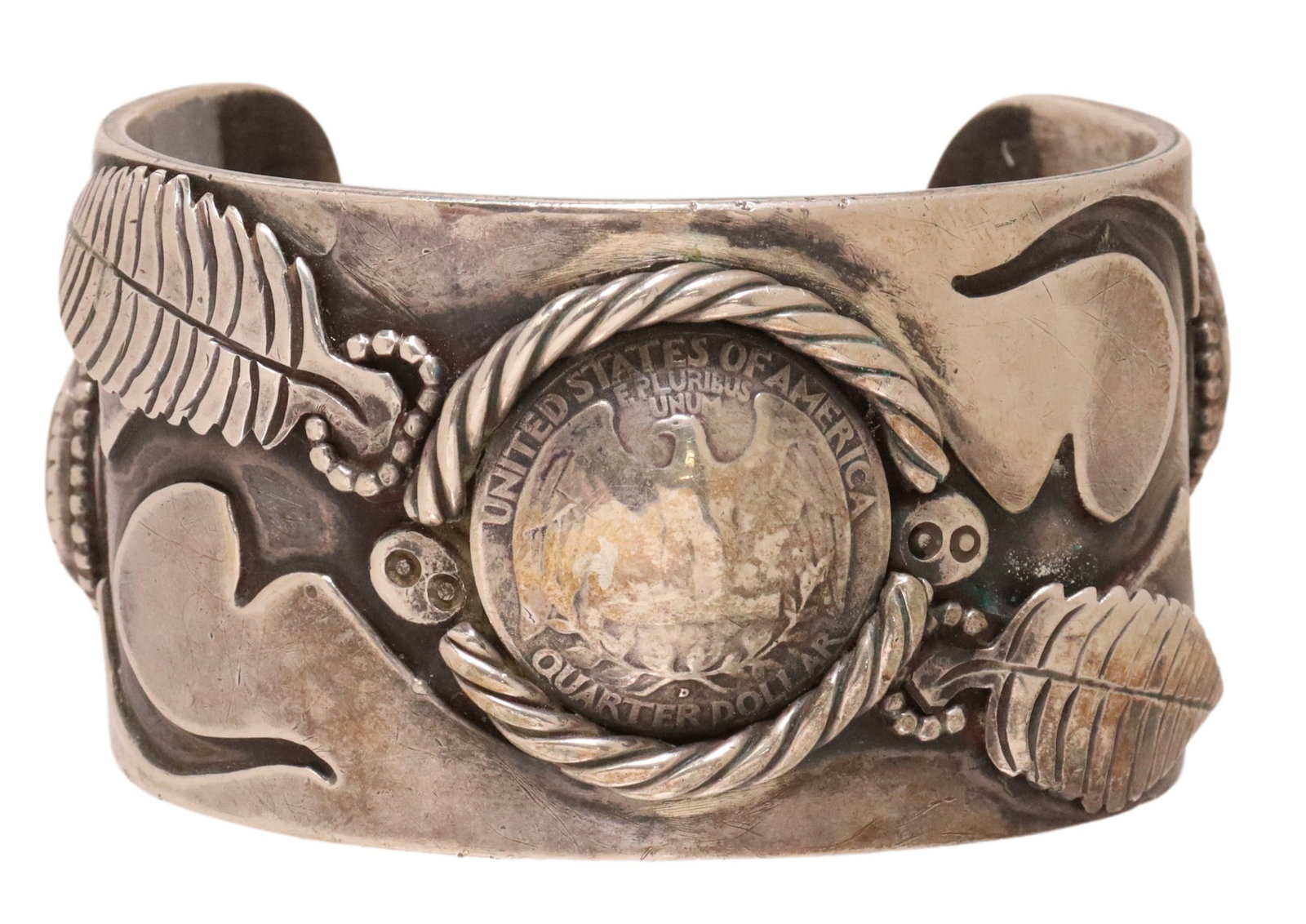 SOUTHWEST SILVER INLAID QUARTER CUFF BRACELET: Southwest silver (content unknown) cuff bracelet, signed LE? or with picto hallmark, central inlaid quarter, flanked by feathers, stampwork, and bezel-set shell cabochons, approx 1.5"w, interior: appr