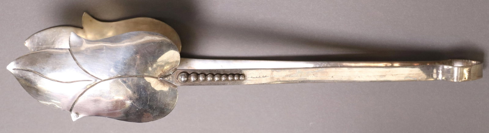 LOS CASTILLO TAXCO STERLING ASPARAGUS TONGS: Handwrought sterling silver asparagus tongs, Los Castillo, Taxco, with blossom-form ends, marked eagle #1 (?), approx 10.75"l, 3.98ozt **Provenance: from the lifetime collection of Ann Baker featuring
