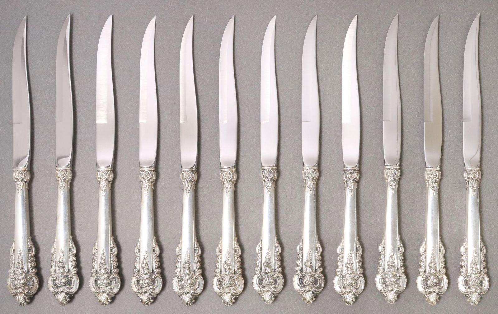 (12) WALLACE GRANDE BAROQUE STERLING STEAK KNIVES: (lot of 12) American sterling silver handled steak knives, Wallace Silversmiths, in the "Grande Baroque" pattern, sterling hollow handles, with stainless steel beveled blades, no observed monograms, a