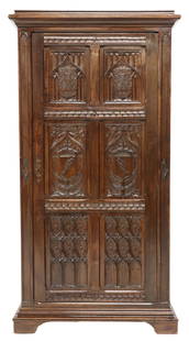 FRENCH GOTHIC REVIVAL ARMORIAL CARVED OAK ARMOIRE: French Gothic Revival carved oak armoire, late 19th c., having stepped cornice, over dual cabinet doors, carved with heraldic shields and tracery motifs, interior fitted for adjustable-height shelves,