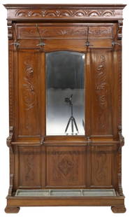 ITALIAN RENAISSANCE REVIVAL MIRRORED HALL TREE: Italian Renaissance Revival walnut hall tree, late 19th c., paneled back with foliate and mask carving, four metal coat hooks above a centered mirror plate, lower umbrella rack and removable metal dri