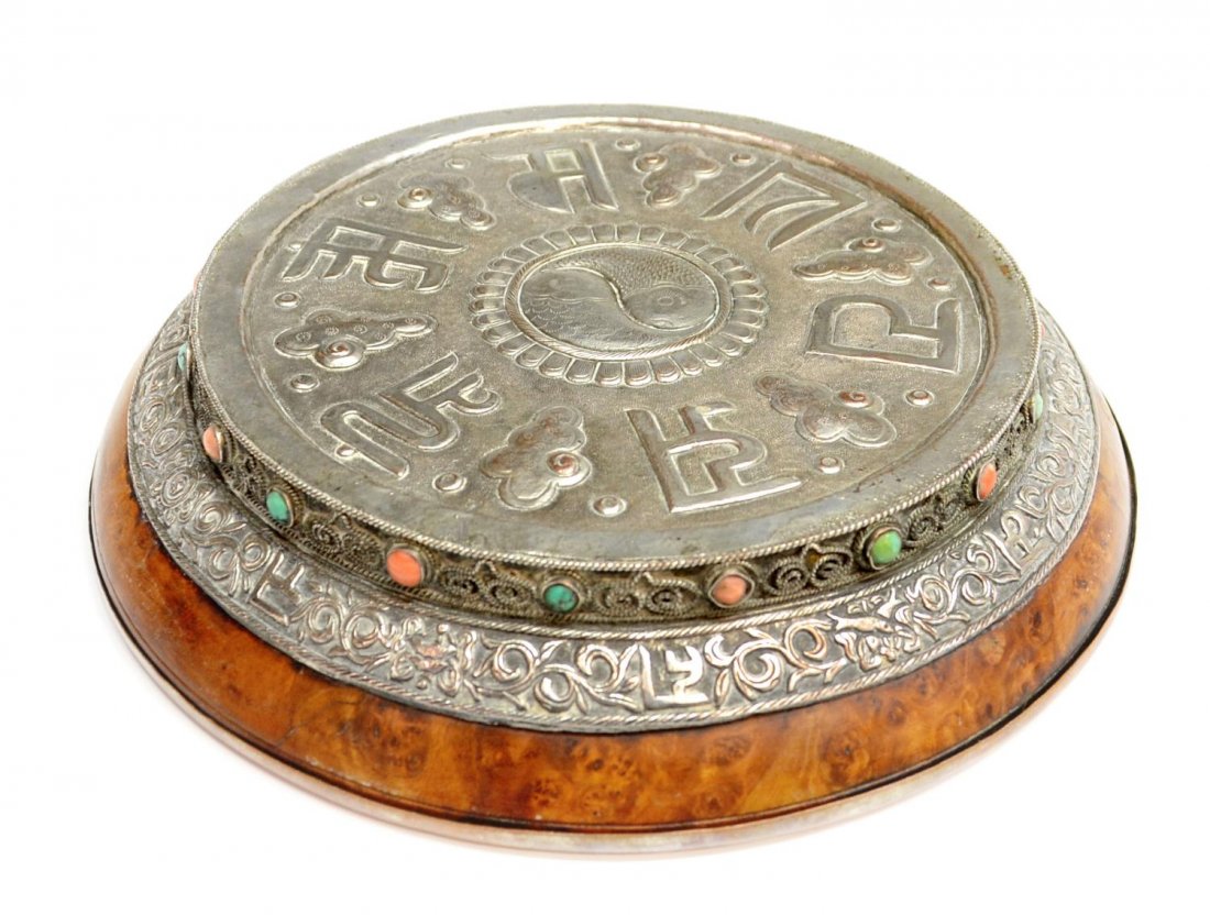 TIBETAN BURLWOOD & REPOUSSE SILVER PLATE ELEMENT: Tibetan repousse silver plate element, the top showing fish, characters and cloud work, foliated border with characters embellished with turquoise and coral cabochons, mounted on a burlwood base with 