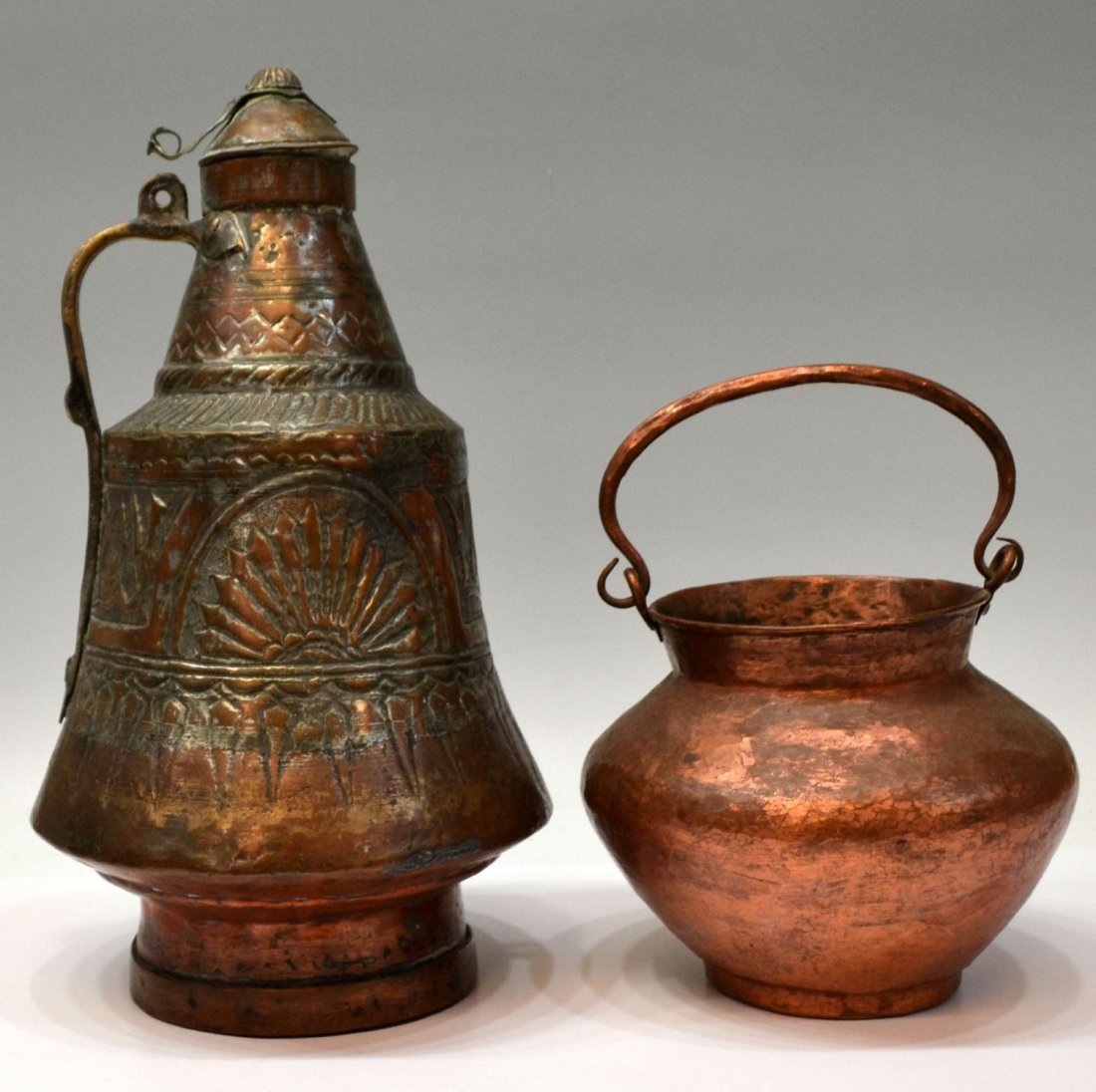 MIDDLE EASTERN COPPER JUG & COPPER POT: (lot of 2) A Middle Eastern copper ewer with lid, Arabic script and sunburst in reserve, lid not attached, some restoration, 17.75"h; together with a hammered copper vessel with swing handle, approx 7