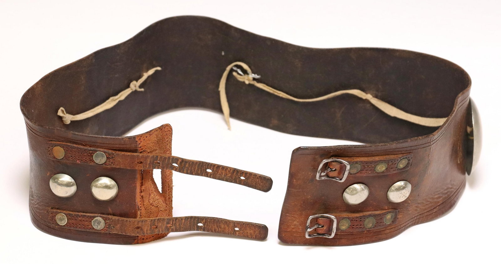 PLAINS INDIAN LEATHER & GERMAN SILVER CONCHO BELT: Plains Indian leather concho belt, nine German silver domed conchos in three varied sizes, on a wide brown leather belt, two riveted straps with tang buckles, largest concho: approx 2.5"diam, belt: ap