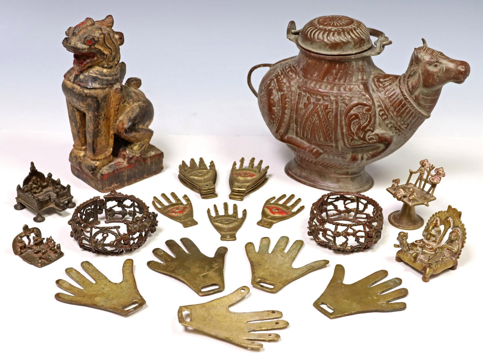 LOT) METALWARE: NANDI VESSEL, HINDU SHRINES, INDIA: (lot) Metalware, highlights include: (1) copper holy water container in the form Nandi the bull vahana of Shiva, (4) miniature shrines/ altars, (18) brass hand amulets, varied designs and sizes, toget