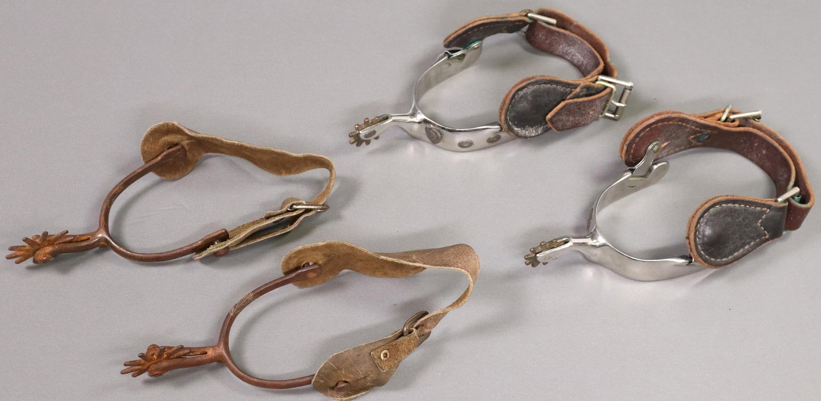 (2 PAIR) COWBOY SPURS, ONE VINTAGE NORTH & JUDD: (2 pair) Cowboy spurs: (1) vintage iron spurs by North & Judd with anchor mark at underside of shank, 10 point 1.75" rowels, calfskin leathers; (1) polished stainless steel, the heel band with mounted