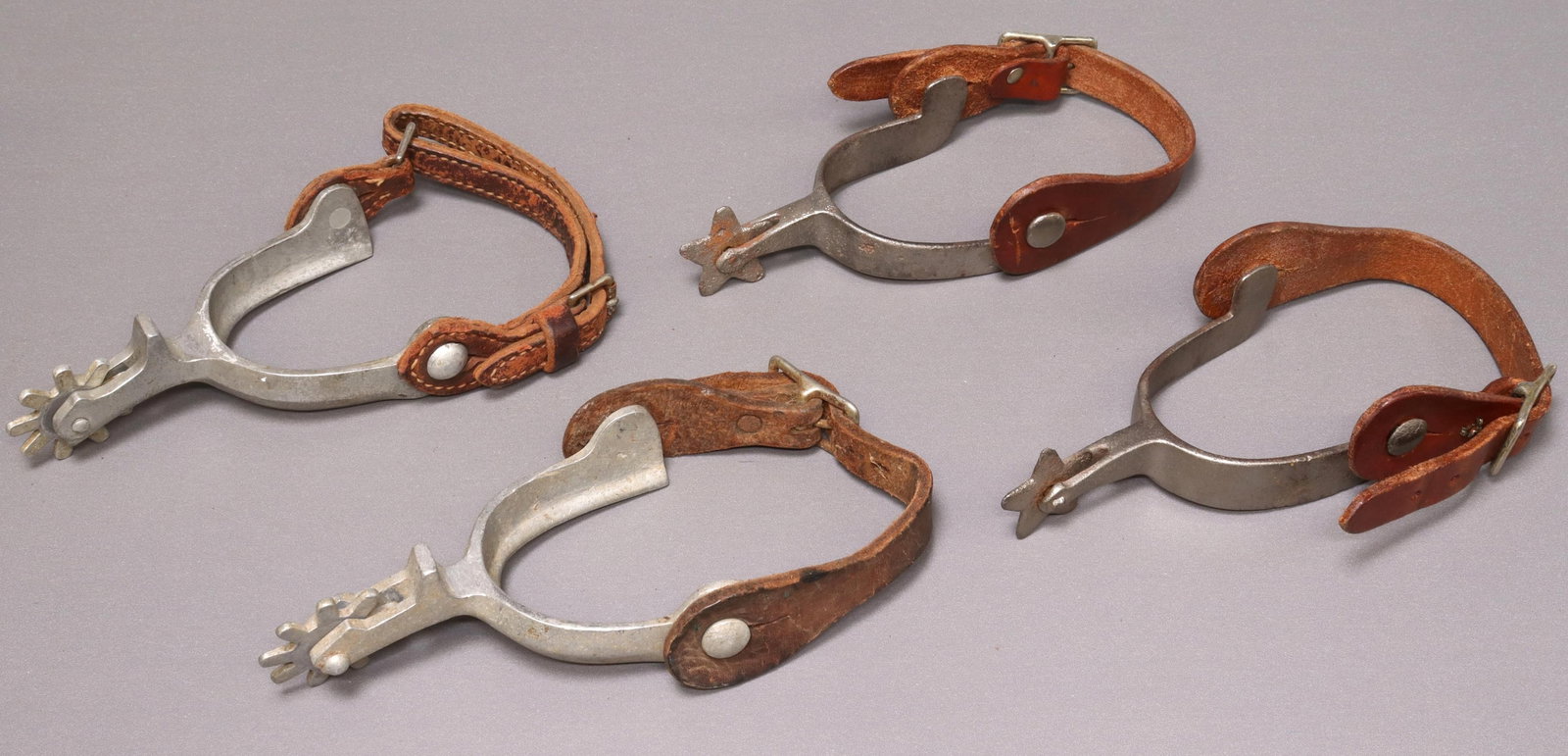 (2 PAIR) COWBOY SPURS, ONE VINTAGE NORTH & JUDD: (2 pair) Vintage cowboy spurs: (1) North and Judd anchor mark at shank underside, five point 1.5" rowels, an old pair with pitted metal; (1) vintage aluminum pair, nine point 1.75" rowels, non matched
