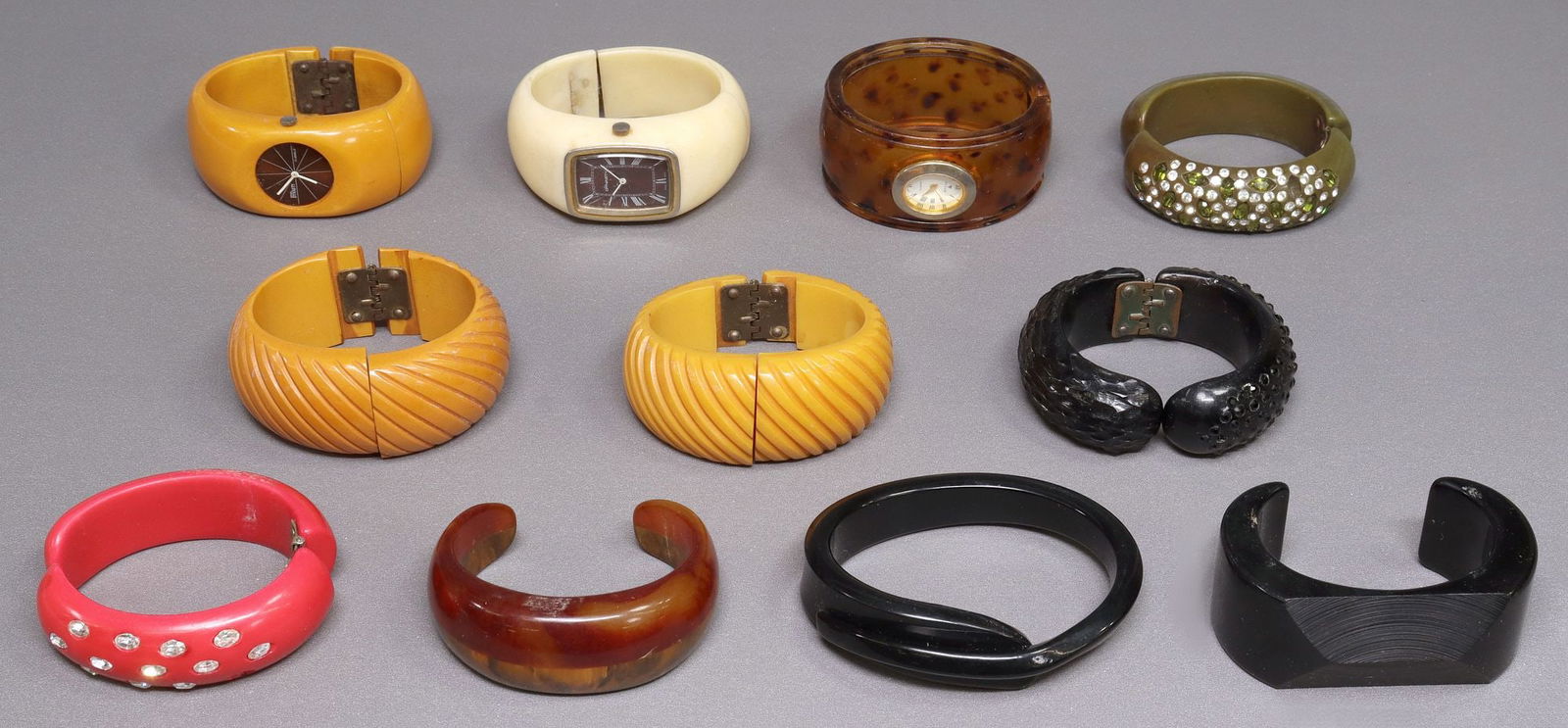 (11) VINTAGE BAKELITE & OTHER PLASTIC WATCH & CLAMPER CUFFS BRACELETS:  (lot of 11) Vintage Bakelite and other plastic cuff bracelets, various colors and designs, highlights include (3) clamper cuffs with rhinestone accents, each missing at least one rhinestone, (2)