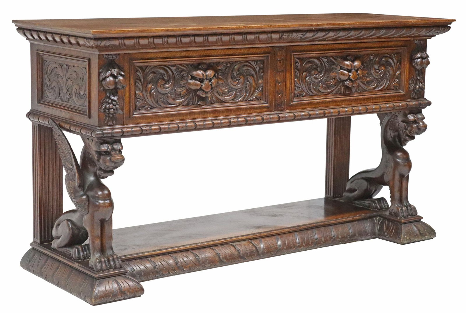RENAISSANCE REVIVAL CARVED OAK SIDEBOARD: English Renaissance Revival carved oak sideboard, 20th c., fitted with two large drawers, faced with grotesque masks, rising on winged mythical beast supports, further ending on foliate carved plinth 