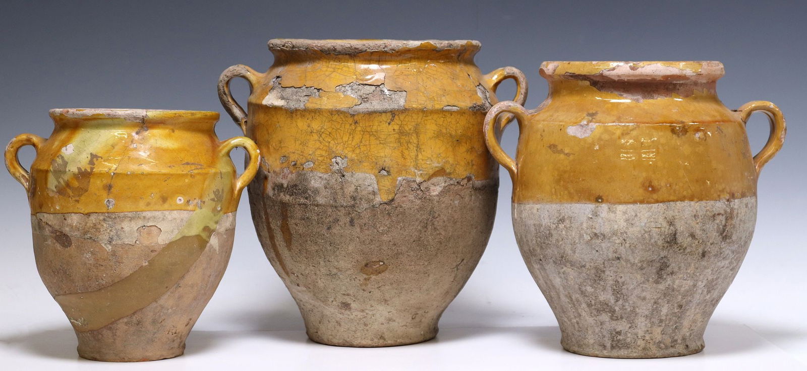 (3) FRENCH YELLOW-GLAZED EARTHENWARE JUGS: (lot of 3) French Provincial earthenware water jugs, with ochre-colored glazed rim, tapered body, dual handles at sides, typical glaze loss and chips, largest: approx 12 3/8"h, 10