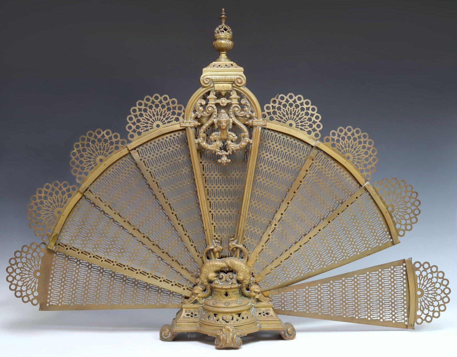 FRENCH GILT METAL FAN FIREPLACE SCREEN: French gilt metal fan fireplace screen, early 20th c., having pierced finial, over cartouche flanked by scrolls, holding folding panel screen, pair of scaled beasts perched on plinth base with quatref
