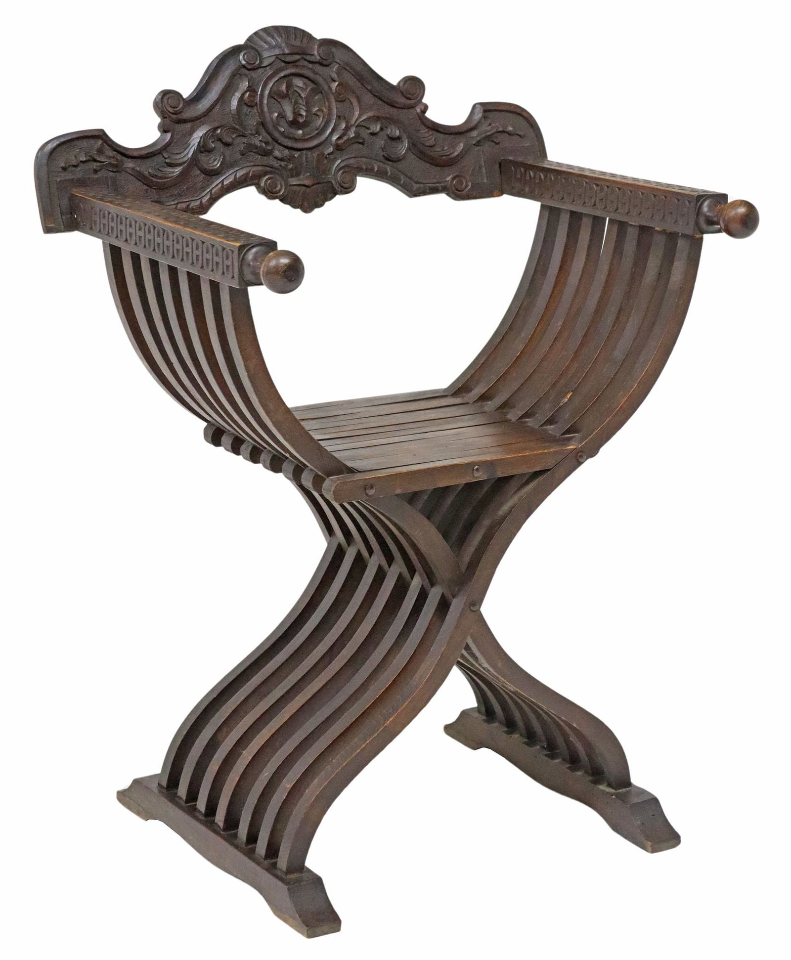 ITALIAN CARVED WALNUT SAVONAROLA ARMCHAIR: Italian carved walnut Savonarola armchair, early 20th c., having carved crest, slatted frame, rising on a molded shoe base, approx 35"h, 26.5"w, 19.5"d, seat height: approx 18.5"h
