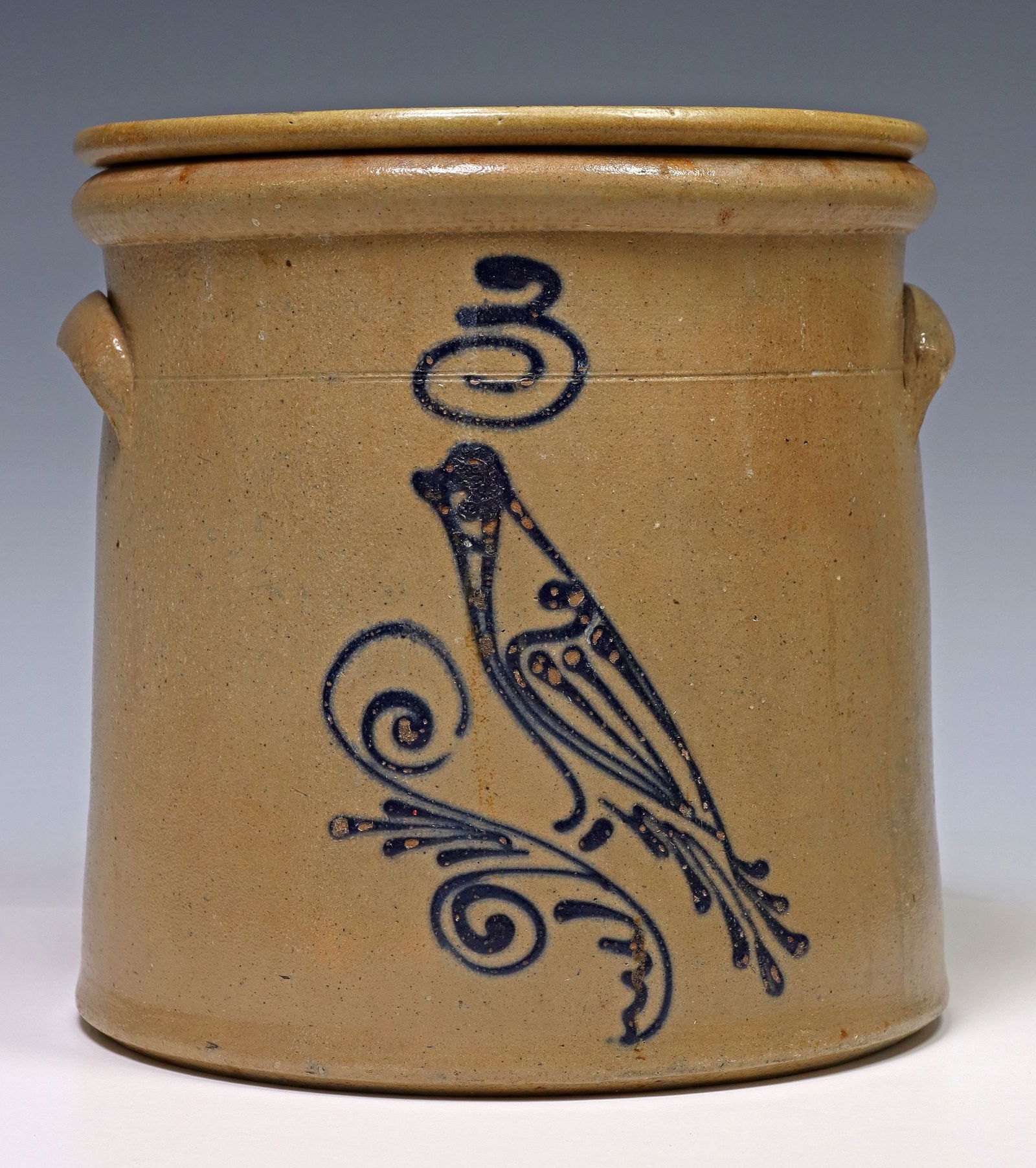 SALT-GLAZED STONEWARE COBALT BIRD THREE-GALLON CROCK & COVER: Salt-glazed stoneware three-gallon crock/ jar and cover, late 19th c., tooled shoulder, applied lug handles, cobalt slip-trailed design of a bird perched on scroll flourish, capacity mark, cover with
