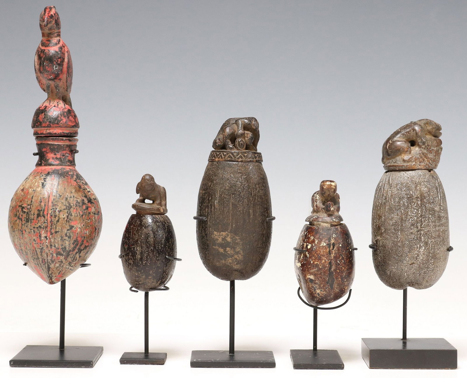 (5) CARVED & PAINTED SEED POD BOXES ON DISPLAY STANDS: (lot of 5) Carved and polychrome painted seed pod boxes, possibly Southeast Asia, varied designs, each having lid modeled as an animal or human figure, accompanied by metal display stand, largest: app