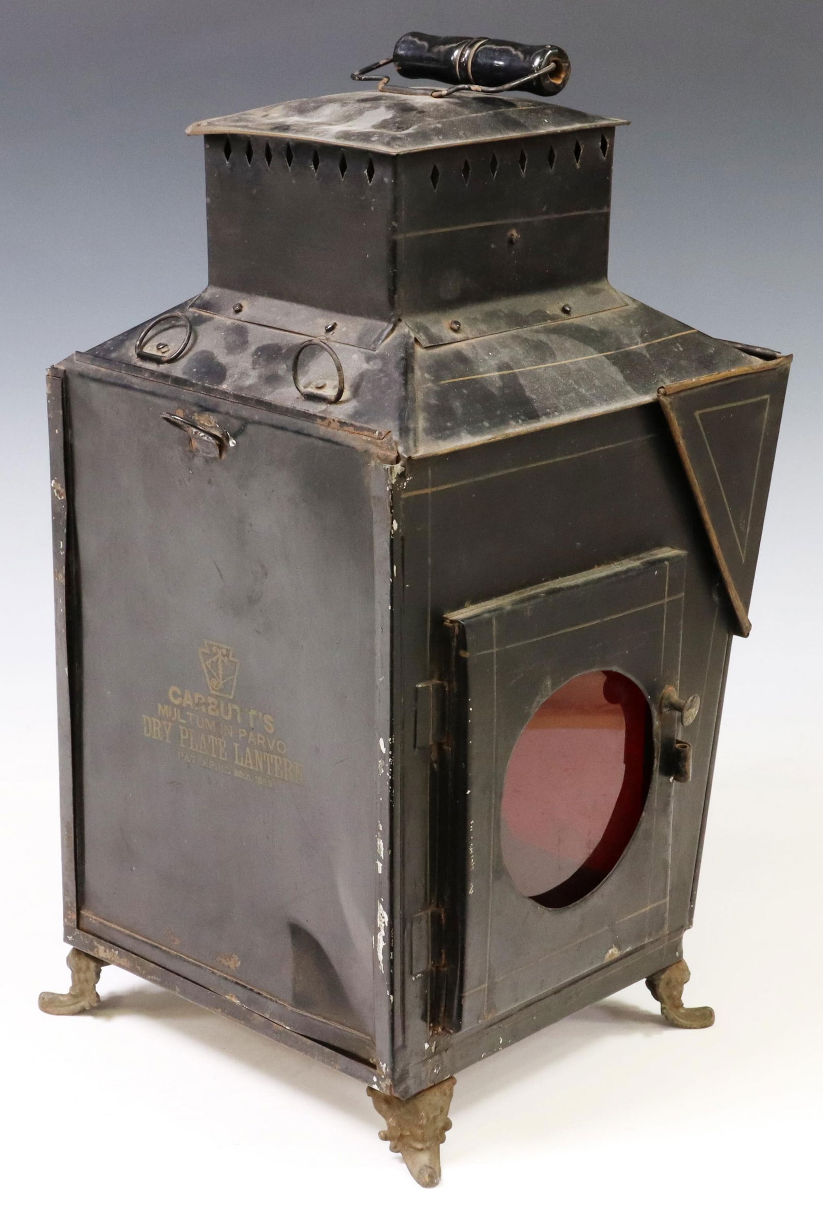 LARGE CARBUTT'S DRY PLATE DARK ROOM LANTERN: Dark room lantern, "Carbutt's, Multum in Parvo, Dry Plate Lantern, Pat. April 25th, 1882", black tin, carry handle at top, doors at two sides, one with red glass, the other with white glass, the front