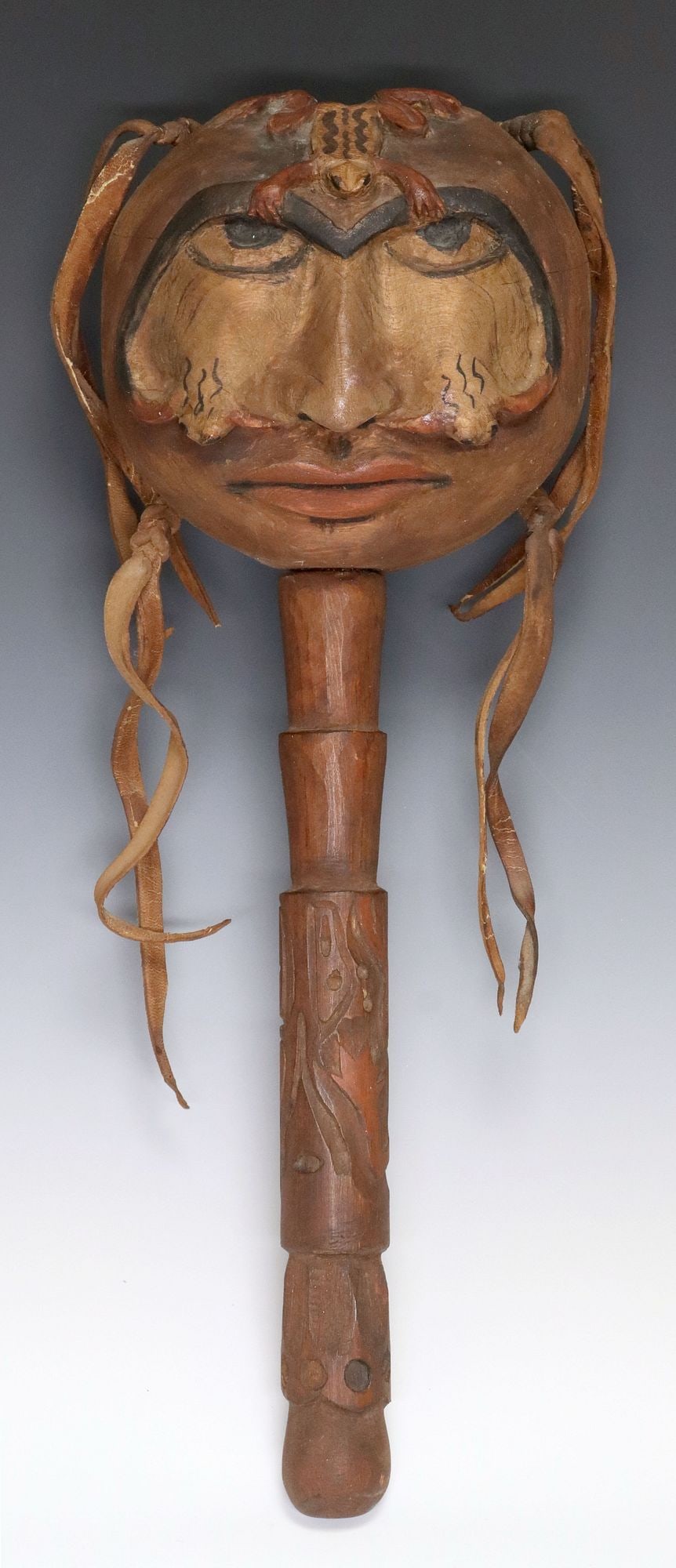 NORTHWEST COAST STYLE CARVED RATTLE, WEEPING FROG: Northwest Coast style carved 'Weeping Frog' rattle, likely last quarter 20thc., the face with painted features and frogs, leather accents, center stem encircled by a carved frog,&nbs