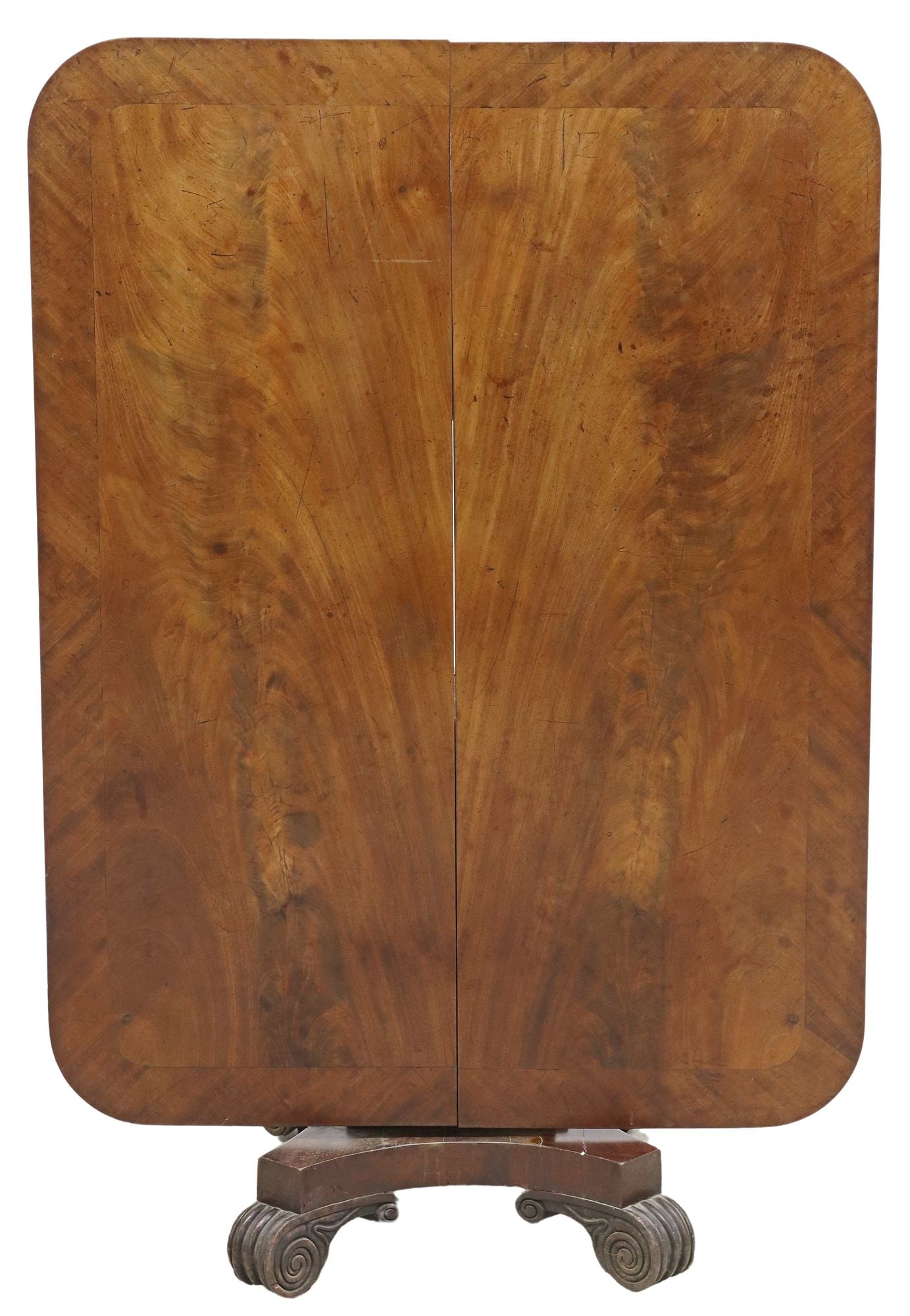 ENGLISH REGENCY BANDED MAHOGANY TILT-TOP BREAKFAST TABLE: English Regency mahogany tilt-top breakfast table, early 19th c., banded rectangular top with rounded corners, center pedestal, shaped base with concave sides, on carved scroll feet, some veneer loss 
