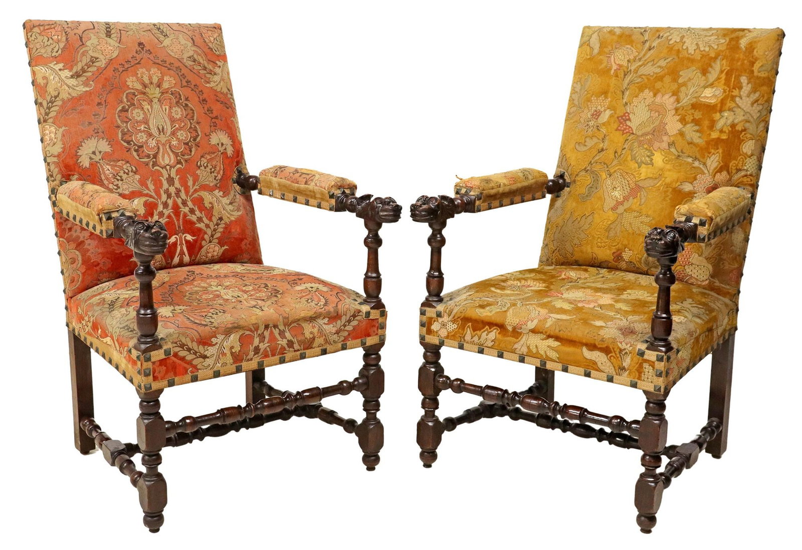 (2) FRENCH LOUIS XIII STYLE HIGHBACK FAUTEUILS: (lot of 2) French Louis XIII style highback armchairs, 19th c., worn varied floral patterned upholstery, carved grotesque mask hand holds, rising on turned stretcher-joined legs, in need of new uphols