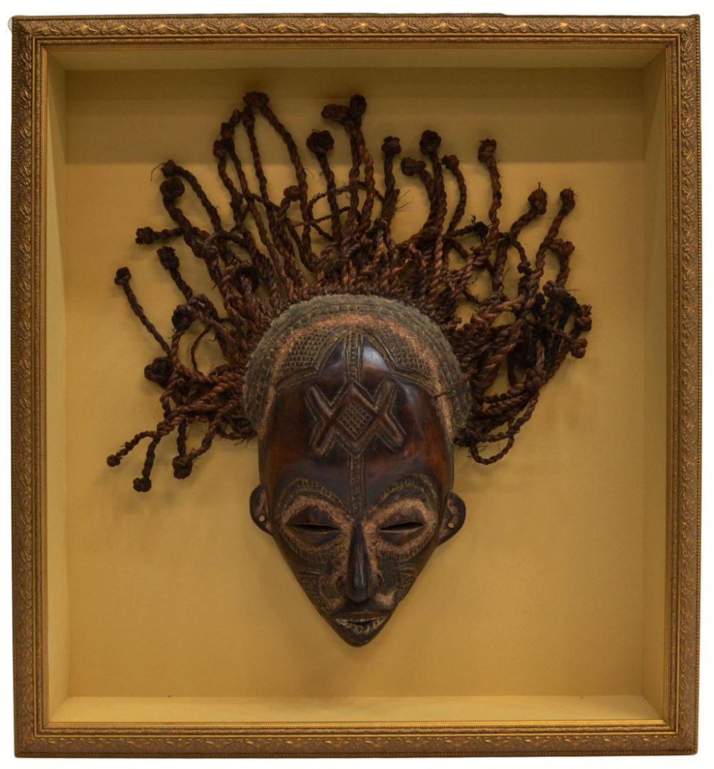 FRAMED AFRICAN WOOD TRIBAL MASK: Shadow box framed African carved wood mask, face carved with geometric tribal patterns, splayed rope hair, mask: approx. 20"h, 18"w (inclusive of hair), overall: 26.25"h, 24.25"w, 11.25lbs Start Price
