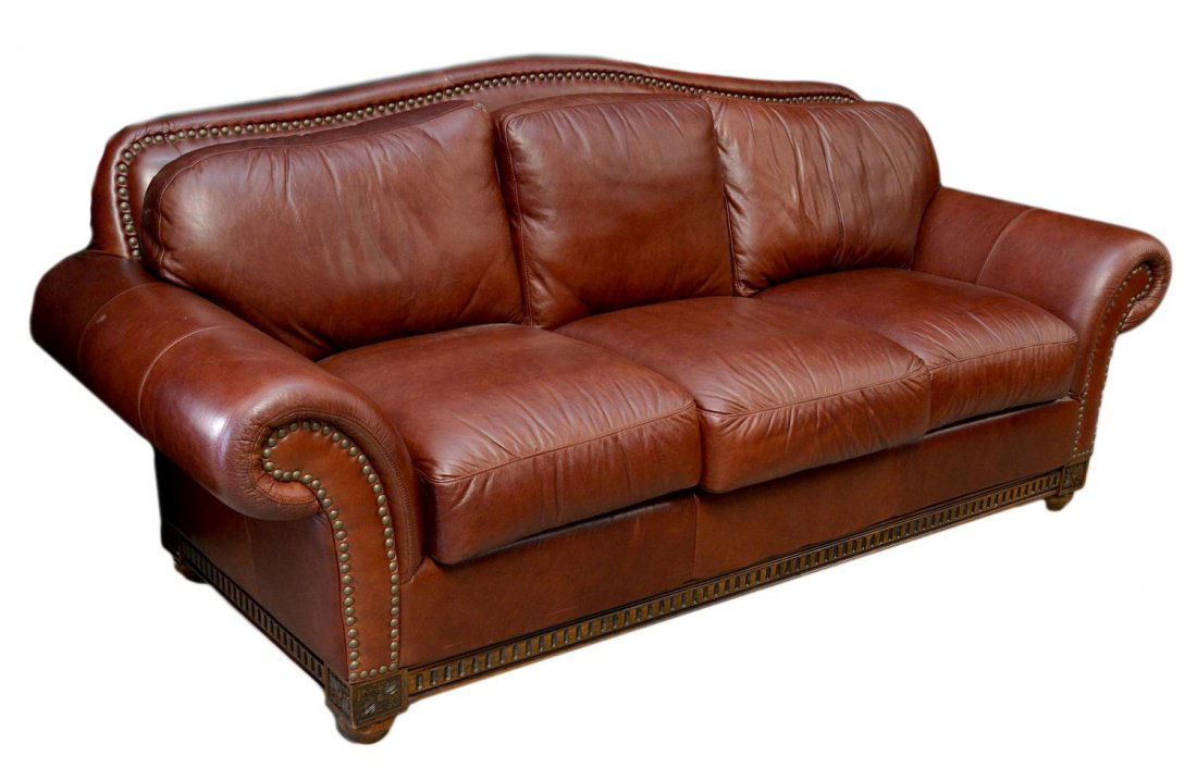 JOHN WILLIAMS INTERIOR LEATHER SOFA NAIL HEAD TRIM: Fine John Williams Interior leather sofa of generous proportion, the gently curved back joined to plush arm rests, all accented with large brass nail heads, carved floral heads on each corner of the c