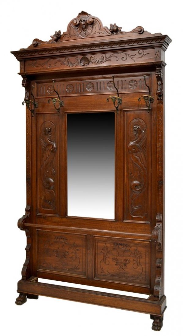 ITALIAN RENAISSANCE REVIVAL WALNUT HALL TREE: Italian Renaissance Revival style walnut hall tree, c. 1900, a central mirror flanked by carved winged griffin panels, lower umbrella rail, rising on claw feet, 93"h, 47"w, 8.5"d Start Price: $250.00
