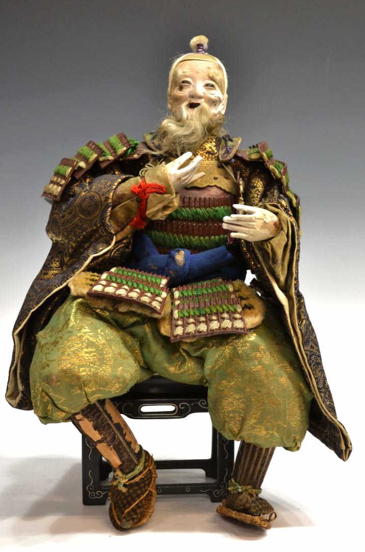 ELABORATELY COSTUMED JAPANESE WARRIOR DOLL: Japanese warrior doll (musha-ningyo), 19th/early 20th century, seated in traditional armor and gilt brocade garments, depicting the elderly minister Takenouchi no Sukune (now lacking the infant Ojin) 
