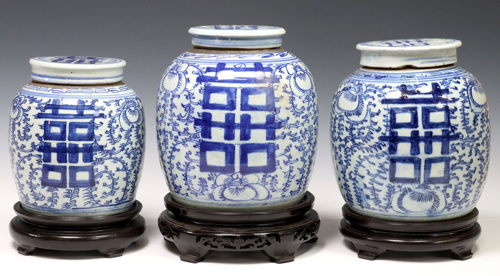 (3) CHINESE BLUE & WHITE PORCELAIN COVERED GINGER JARS ON STANDS: (lot of 3) Chinese blue and white porcelain lidded ginger jars, each with floral blossoms and double happiness characters, scrolled ground, rising on wood stand, one intact with hairline to lid, some 