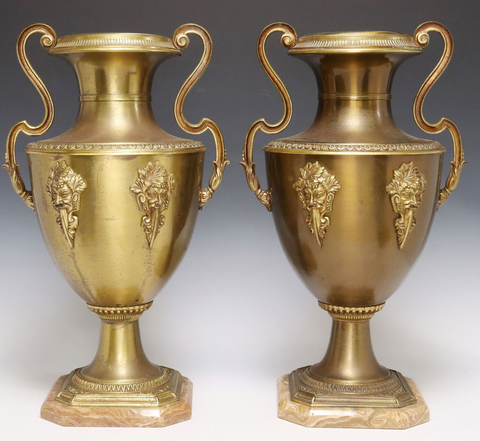 (2) GILT METAL BACCHUS AMPHORA-FORM GARNITURES/ VASES: (pair) Gilt metal amphora-form garnitures/ vases, 20th c., having dual scrolled handles, raised figural faces around body depicting Bacchus, running ornamentation throughout, each