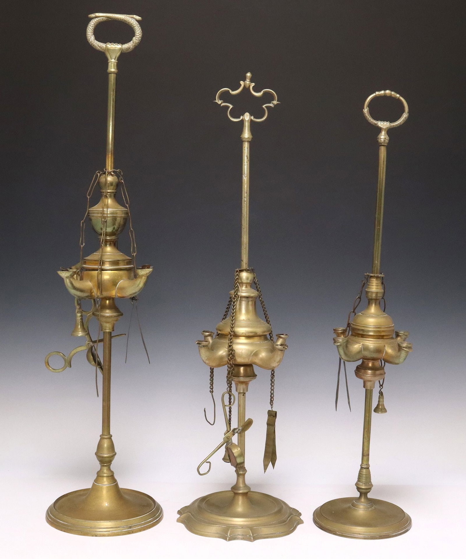 (3) CONTINENTAL BRASS FOUR-SPOUT WHALE OIL LAMPS: (lot of 3) Continental brass whale oil lamps, late 19th c., each with shaped top handles, four spouts with wick trimmer and pick tools on link chain, rising on round base with wax-catching well, appro