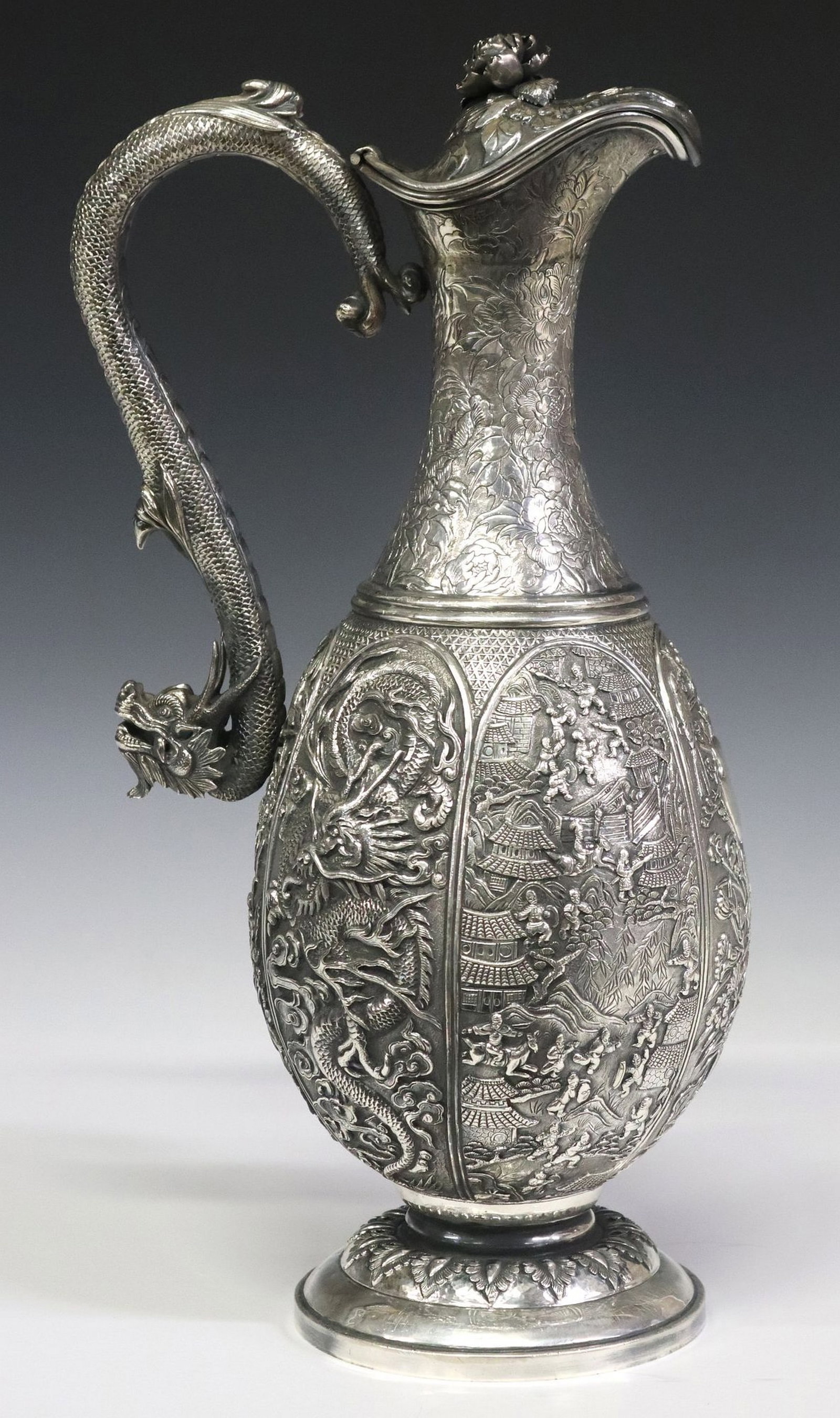 LARGE WOSHING CHINESE EXPORT SILVER DRAGON-HANDLED WINE EWER: Large Chinese Export silver wine ewer, Woshing (fl.1850s-1925), Shanghai, hinged lid with peony flower finial, above the scrolled dragon-form handle, baluster-form body decorated with repousse pictori