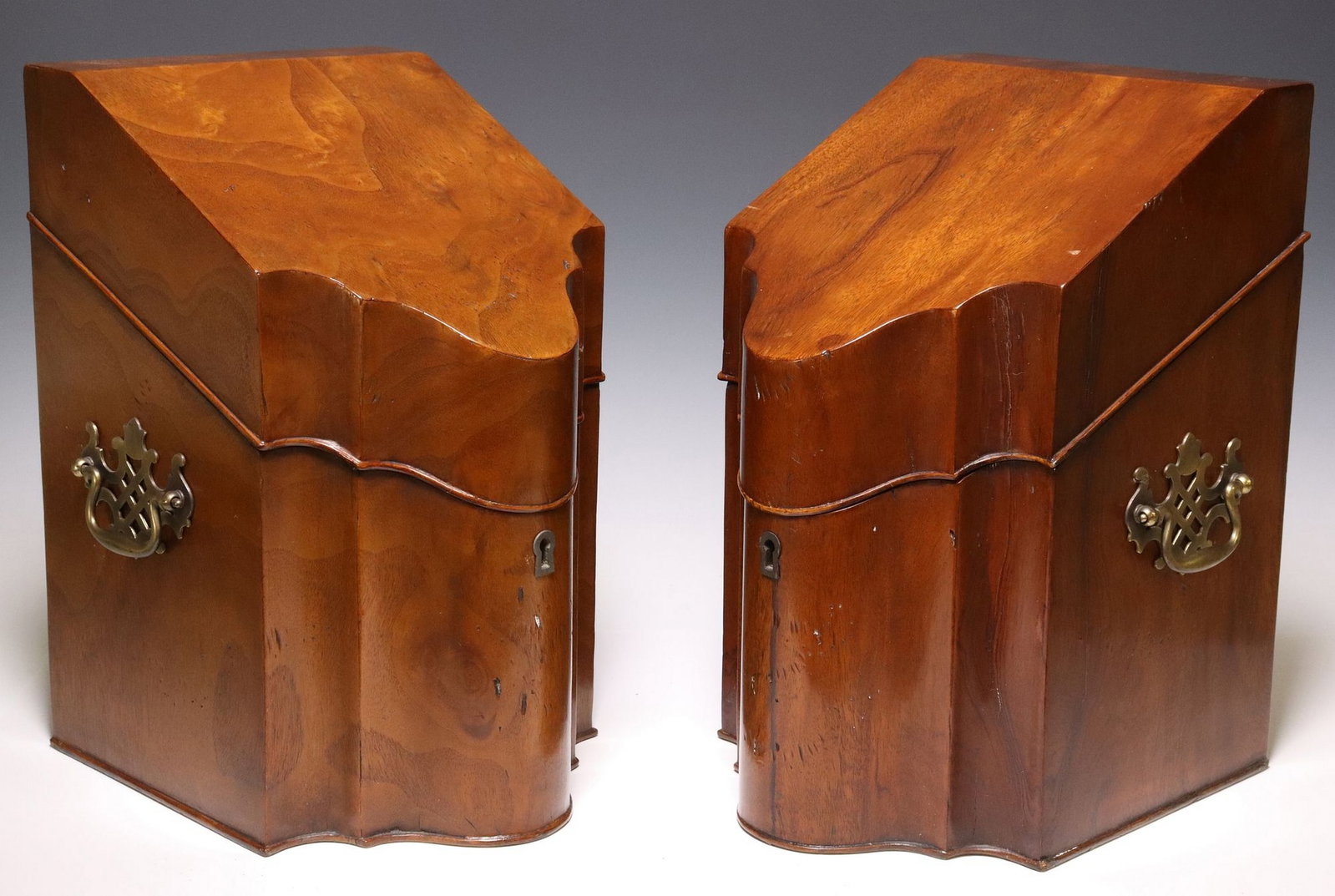 (2) GEORGE III SERPENTINE MAHOGANY KNIFE BOXES NOW STATIONERY BOXES: (lot of 2) English George III mahogany knife boxes, early 19th c., of typical form, with a sloped breakfront lid opening to interior now fitted as a stationery box with later divided compart