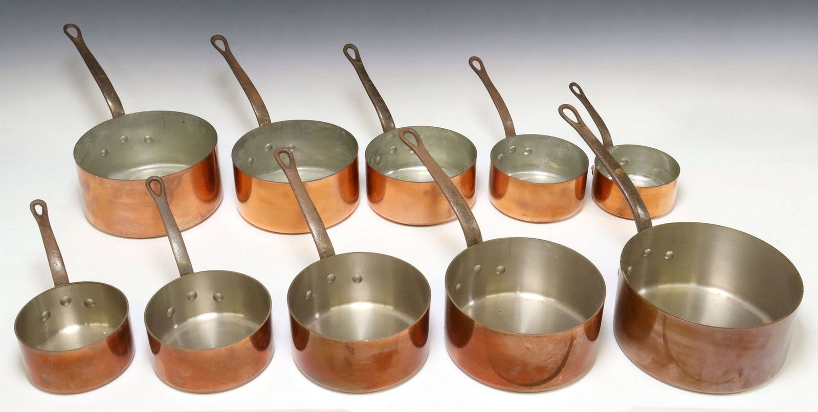 (10) FRENCH COPPER & IRON GRADUATED SAUCEPANS: (lot of 10) French copper graduated saucepans, comprised of two sets, each with iron handle, including: (5) marked Tournus France, largest: approx 7.5"h, 16"w, 8"d; (5) unmarked, l