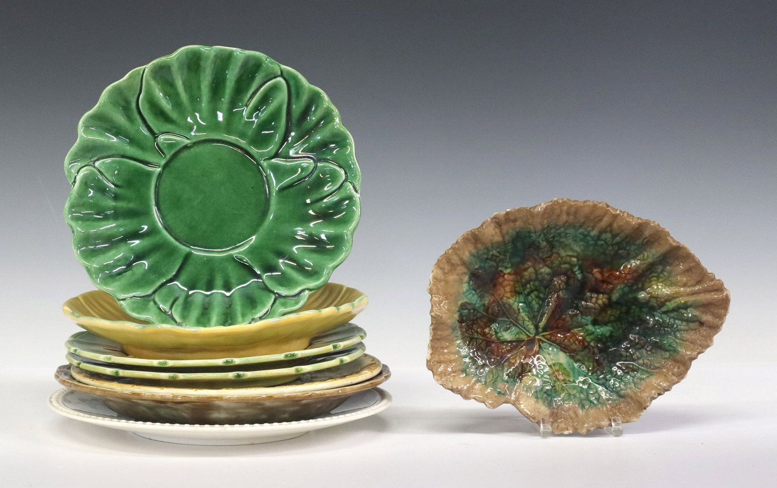(8) COLLECTION OF MAJOLICA PLATES: (lot of 8) Majolica table articles, including: (1) sunflower plate, unmarked, likely English, (1) French Salins parakeets plate, intact with hairlines at rim, (2) French Sarreguemines grape leaves pla