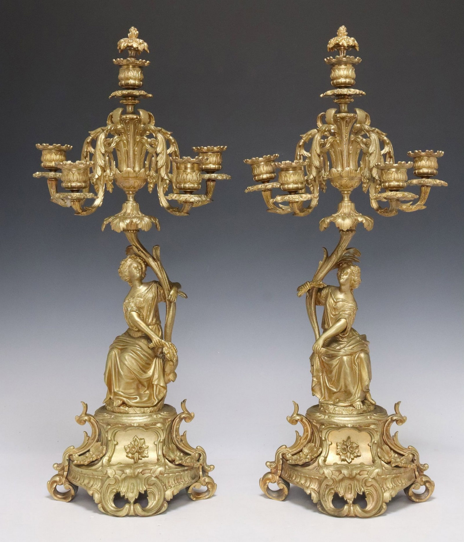 (2) FRENCH GILT BRONZE FIGURAL CANDELABRA: (pair) French gilt bronze candelabra, 19th c., modeled as opposing female beauties in gown and drapery, each holding a foliate stem, issuing four scroll arms terminating at bobeche and candlestic