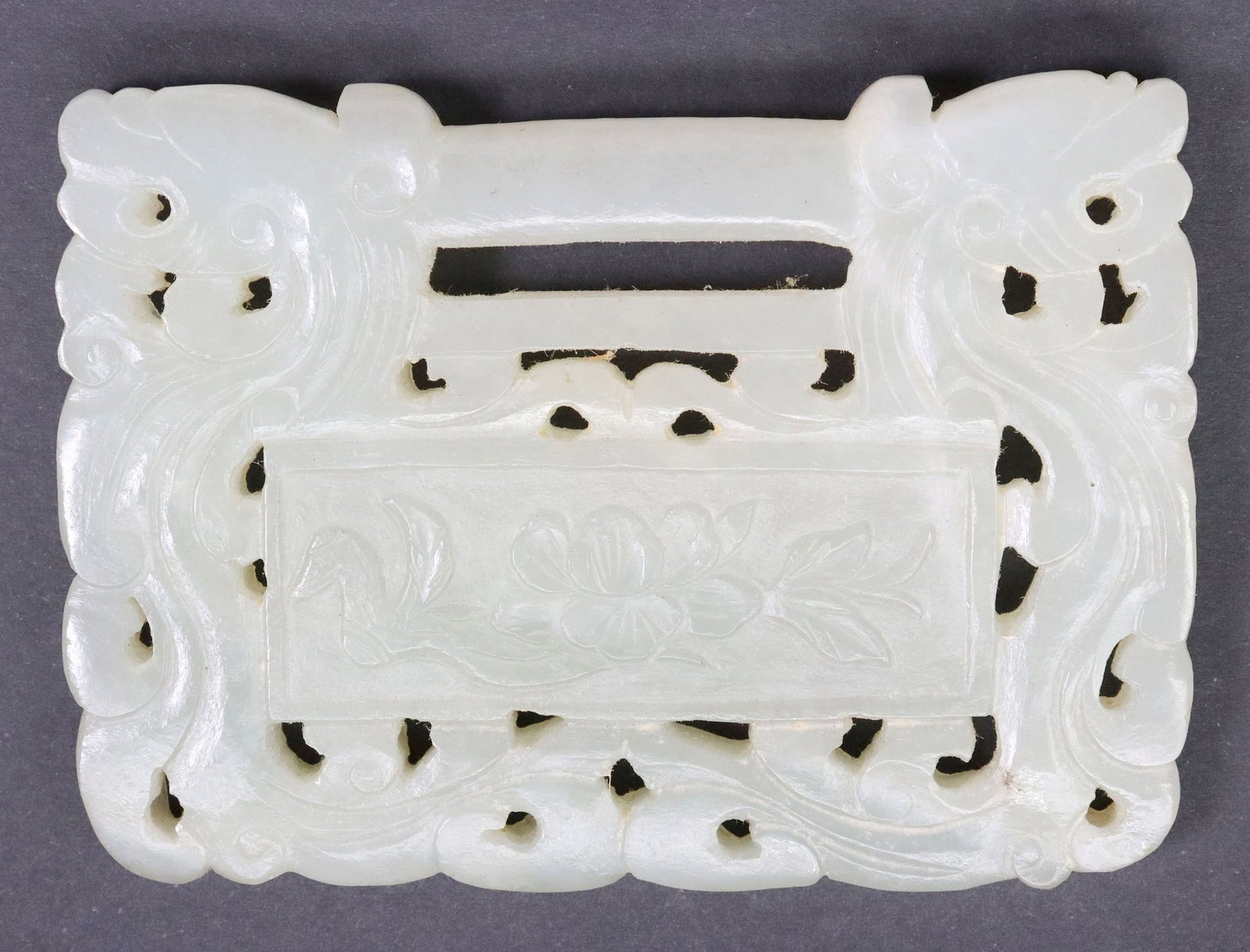 CHINESE CARVED GREEN HARDSTONE RECTANGULAR PENDANT PLAQUE: Chinese carved green hardstone pendant plaque, of rectangular form, central bar flanked by two opposing dragon heads, above pierced body with cloud scrollwork, one side revealing bird and lotus flower