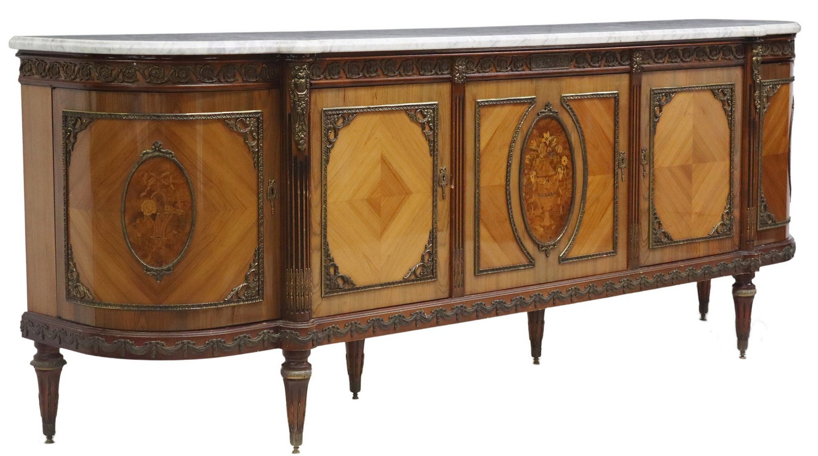 FRENCH LOUIS XVI STYLE MARBLE-TOP MARQUETRY SIDEBOARD: French Louis XVI style matched veneer sideboard, 20th c., having shaped marble top, above five cabinet doors, with gilt metal trim and fluted corner posts, three cartouches with inlaid urns, ribbons, 