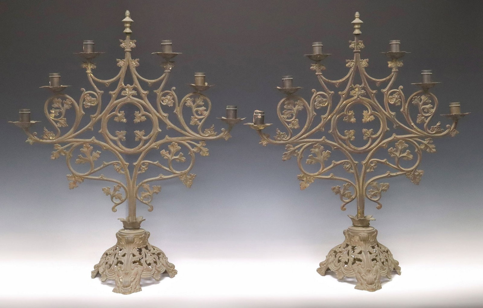 (2) GOTHIC REVIVAL PATINATED METAL 6-LT SCROLLED CANDELABRA: (pair) Gothic Revival patinated metal six-light candelabra, 20th c., each having turned-form finial and six scalloped bobeches, above scrolled foliate frame with central quatrefoil, rising on pi