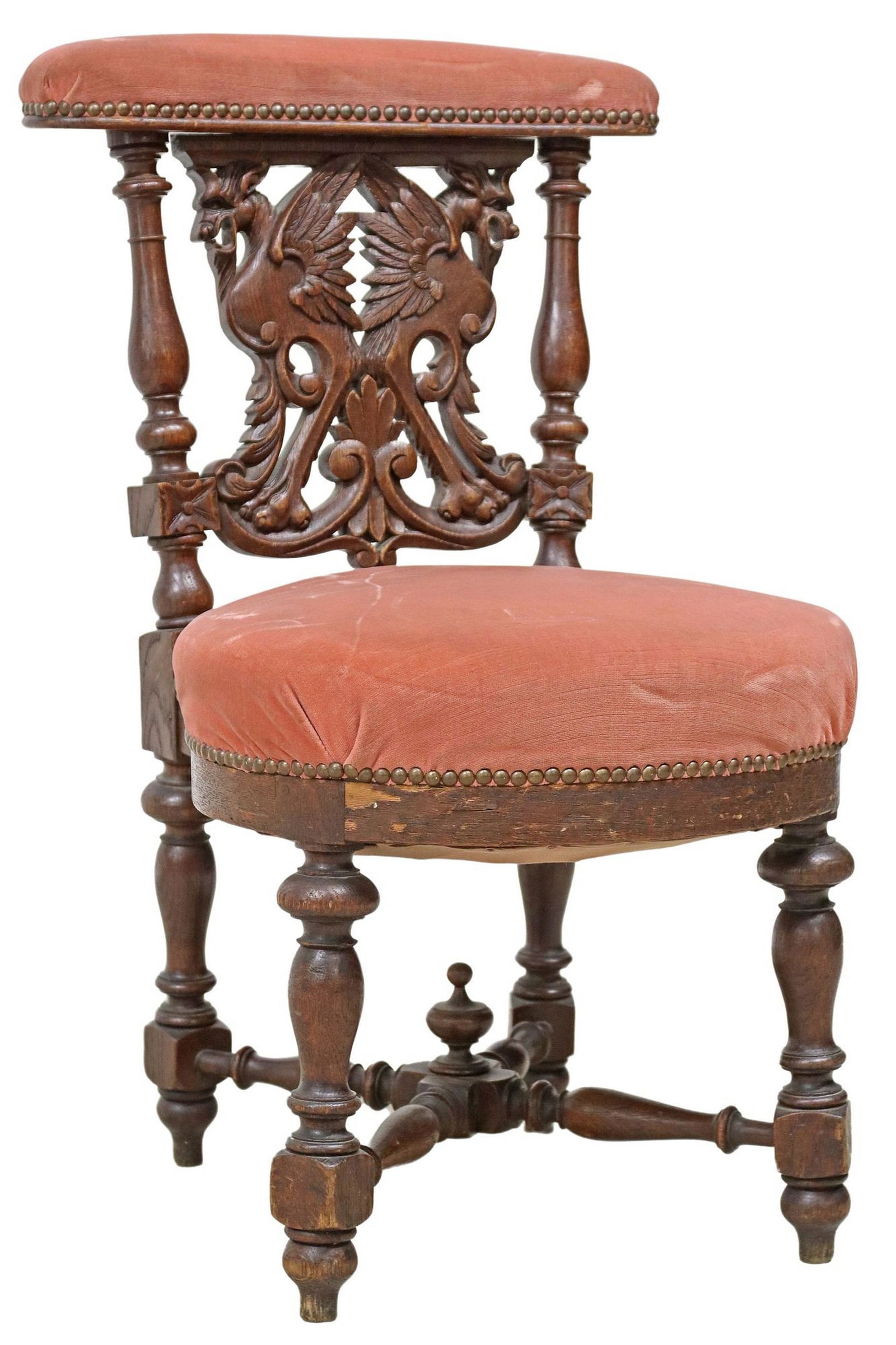 FRENCH CARVED OAK UPHOLSTERED FUMEUSE/ SMOKING CHAIR: French carved oak fumeuse/ smoking chair, late 19th c., having padded seat and top rail in pink fabric upholstery, with nailhead trim, pierced back with opposing winged grotesques, rising on stretcher