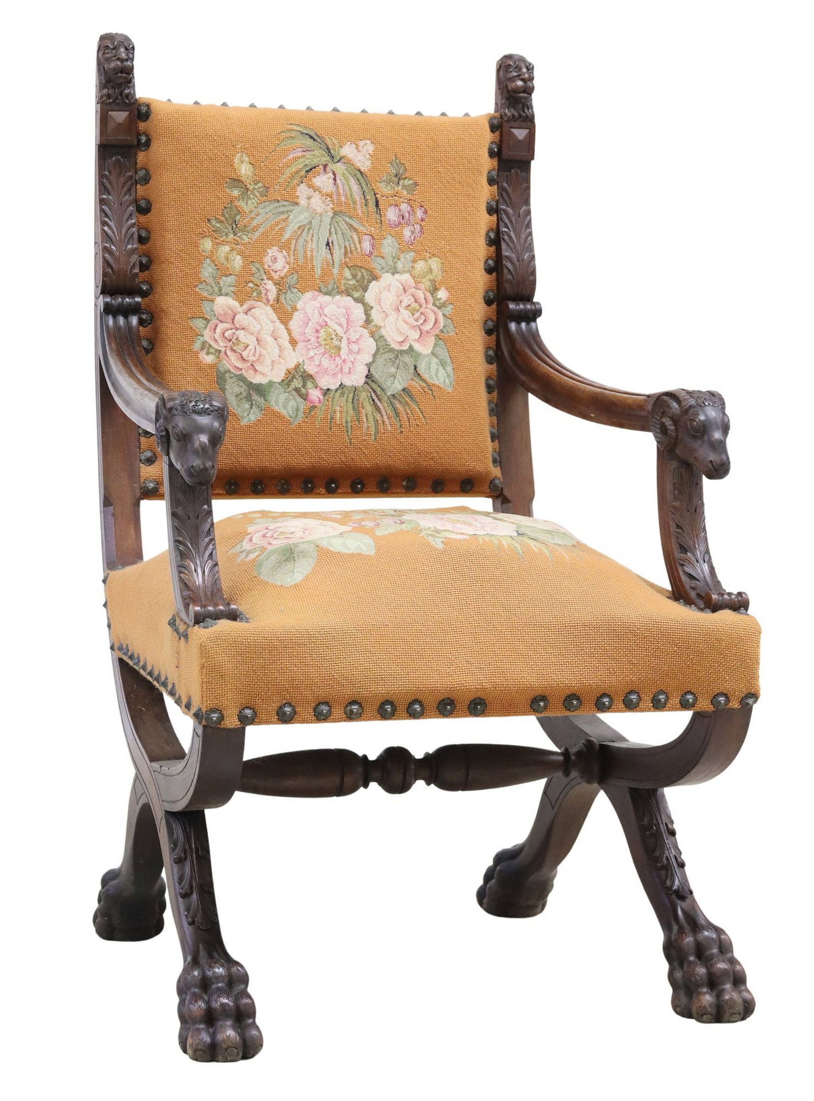 FRENCH RENAISSANCE REVIVAL NEEDLEWORK WALNUT CURULE ARMCHAIR: French Renaissance Revival carved walnut armchair, early 20th c., in floral needlework upholstery, armrests with ram head handholds, rising on curule base, ending in paw feet, upholster