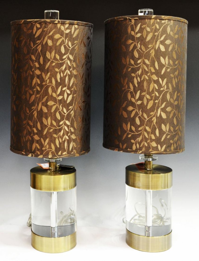 PAIR JOHN RICHARD CYLINDRICAL GLASS TABLE LAMPS: (pair) John Richard table lamps, metal trim on each substantial cylindrical glass base surmounted by a brown shade decorated in bronze-colored leaves, overall: 30.25"h, 5.75"w (base); shade: 10"d, 35l