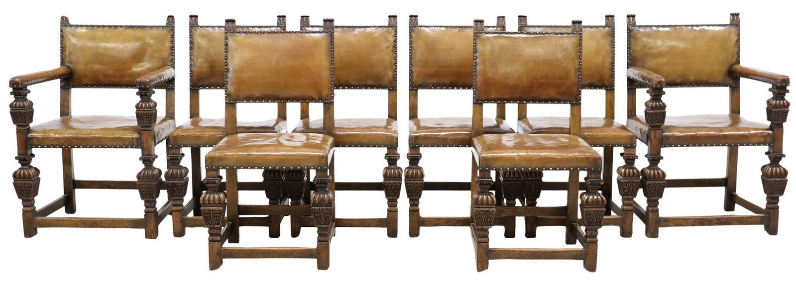 (8) ENGLISH OAK & LEATHER SIDE & ARMCHAIRS: (lot of 8) English Jacobean style carved oak chairs, early 20th c., each with foliated finials at either side of seat back, the seat and back in a tan leather upholstery, rising on shaped and reeded s